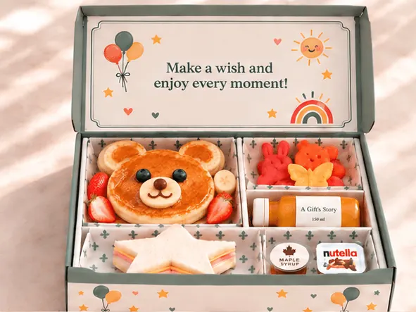 A children’s birthday box opening to reveal a teddy-bear-head pancake with strawberry and banana, star sandwich, fruit and colourful birthday artwork